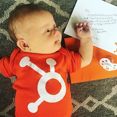 a newborn baby wearing a HubSpot onesie